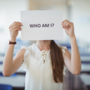 Frau hält Zettel vor ihr Gesicht, auf dem steht "Who Am I? Wer bin ich?", Bloggerpersönlichkeit, Du bist nicht dein Blog