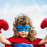 Siegerpose: Ein junges Mädchen im Superheldinnenkostüm mit Boxhandschuhen reckt seine Hände in die Höhe. Leser erreichen, besser texten, Texte schreiben, Kunden überzeugen, Leser überzeugen