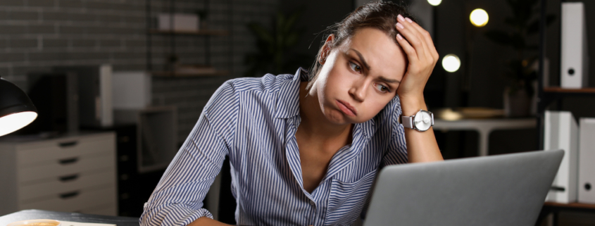 Frau sitzt gestresst und überfordert am Laptop. Symbolbild für verzetteln beim Bloggen