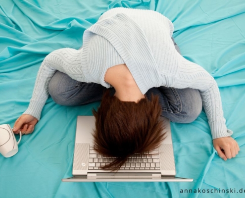 Frau sitzt auf dem Bett und hängt mit dem Kopf auf ihrem Laptop, Blognacht, produktiv bloggen, Networking