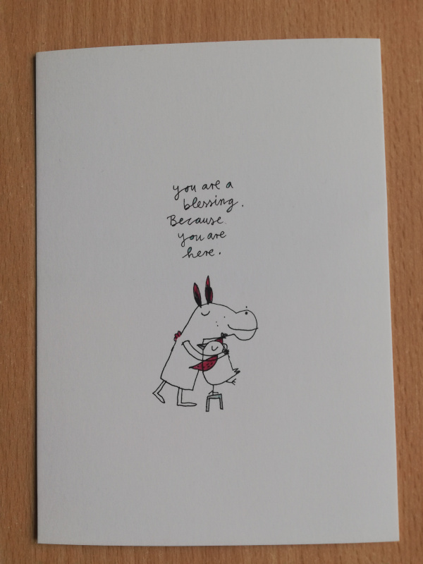 Postkarte. Motiv: Eine Zeichnung: Ein Esel und ein Vogel umarmen sich. Text: "You are blessing. Because you are here."